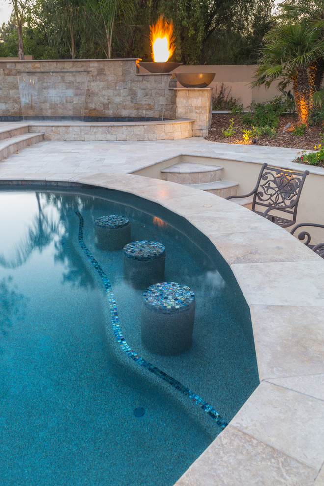 Imagen de piscina con fuente mediterránea grande a medida en patio trasero con suelo de baldosas