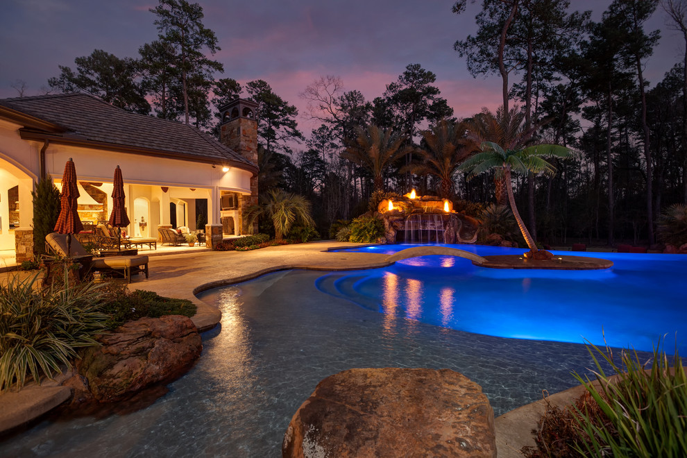 Design ideas for a large classic back custom shaped natural swimming pool in Houston with brick paving and a water feature.