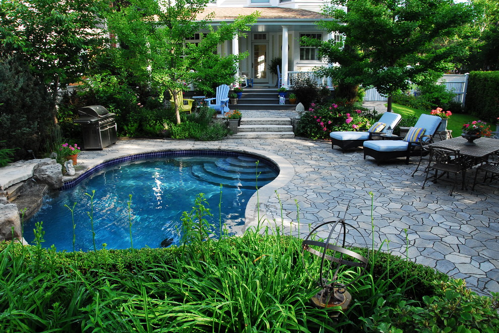 Diseño de piscina con fuente alargada de estilo americano grande tipo riñón en patio trasero con adoquines de piedra natural