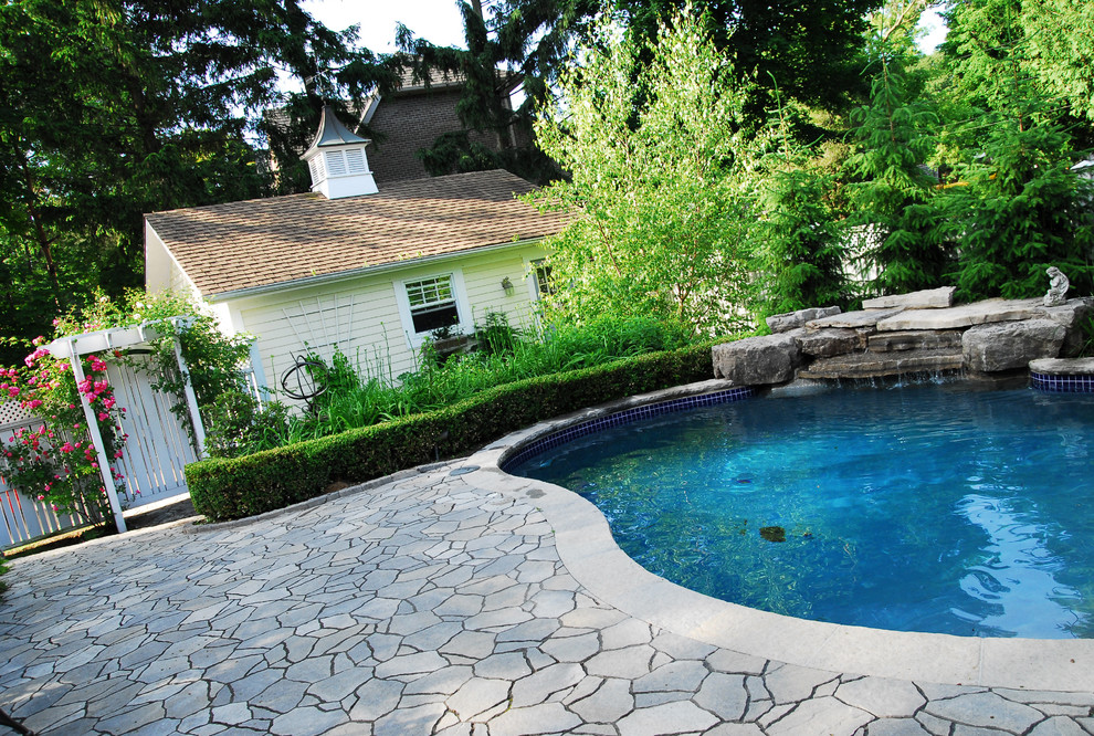 Design ideas for a large classic back kidney-shaped lengths swimming pool in Toronto with a water feature and natural stone paving.