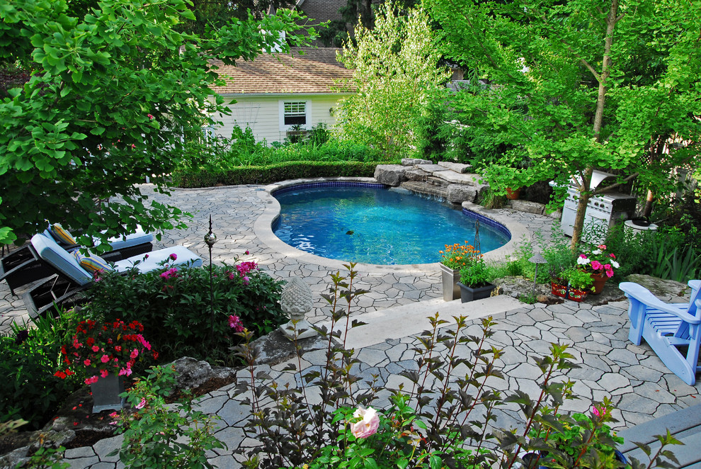 Esempio di una grande piscina monocorsia american style a "C" dietro casa con fontane e pavimentazioni in pietra naturale