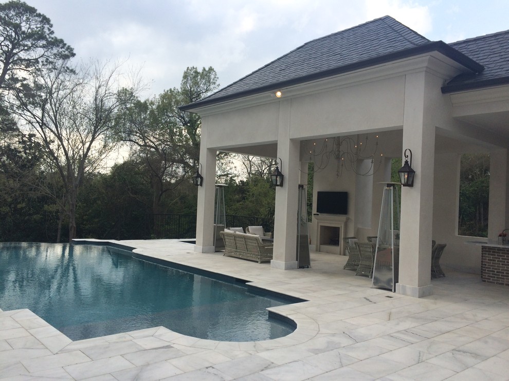 Ejemplo de piscinas y jacuzzis infinitos clásicos extra grandes a medida en patio trasero con suelo de baldosas