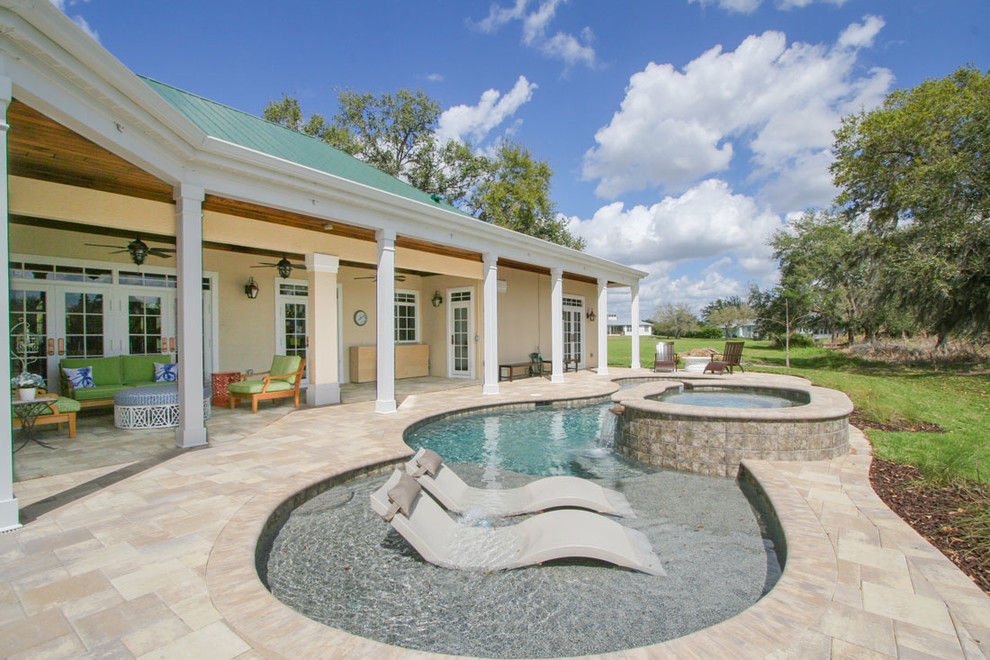 Esempio di una grande piscina stile marinaro personalizzata dietro casa con pavimentazioni in cemento e una vasca idromassaggio