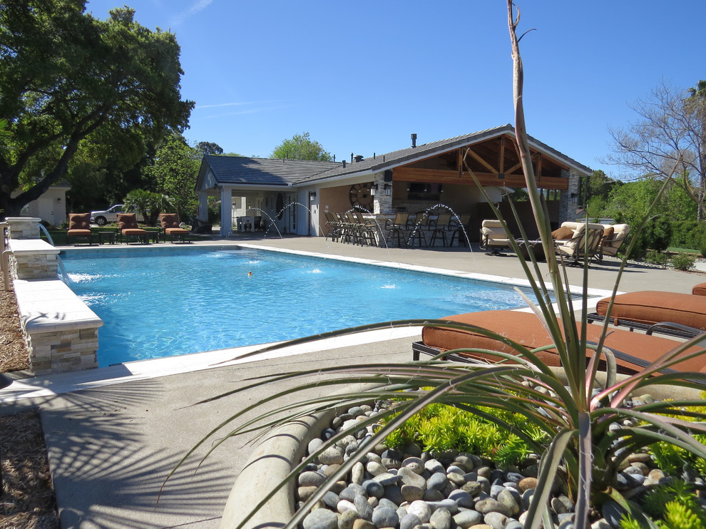 Immagine di una grande piscina american style dietro casa con lastre di cemento