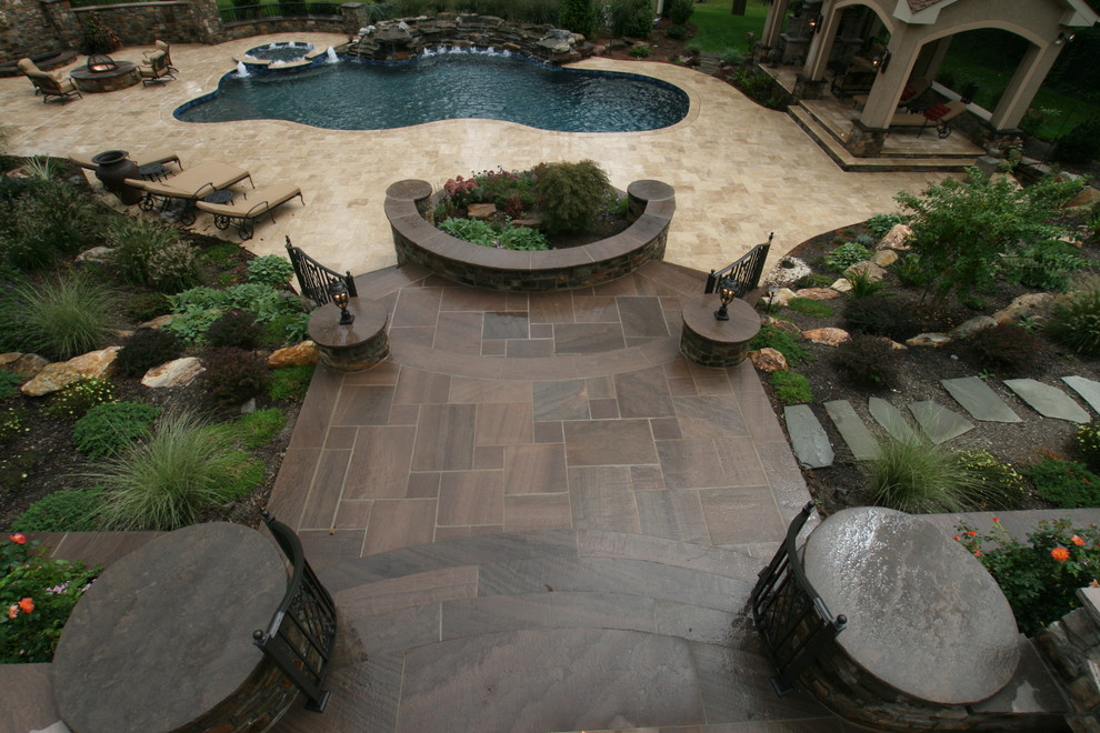 Идея дизайна: большой бассейн произвольной формы на заднем дворе в стиле шебби-шик с джакузи и покрытием из каменной брусчатки