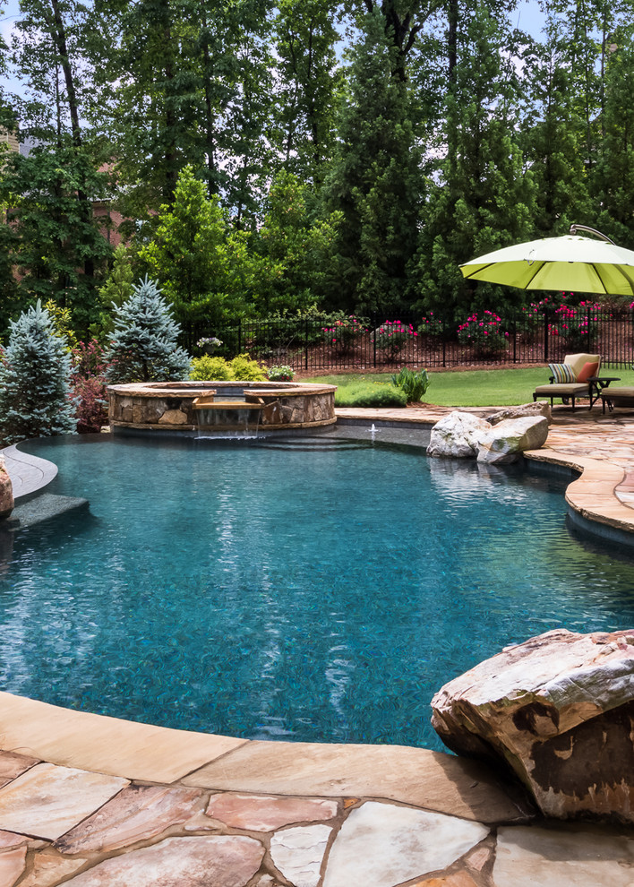 Imagen de piscinas y jacuzzis infinitos tradicionales extra grandes a medida en patio trasero con adoquines de piedra natural