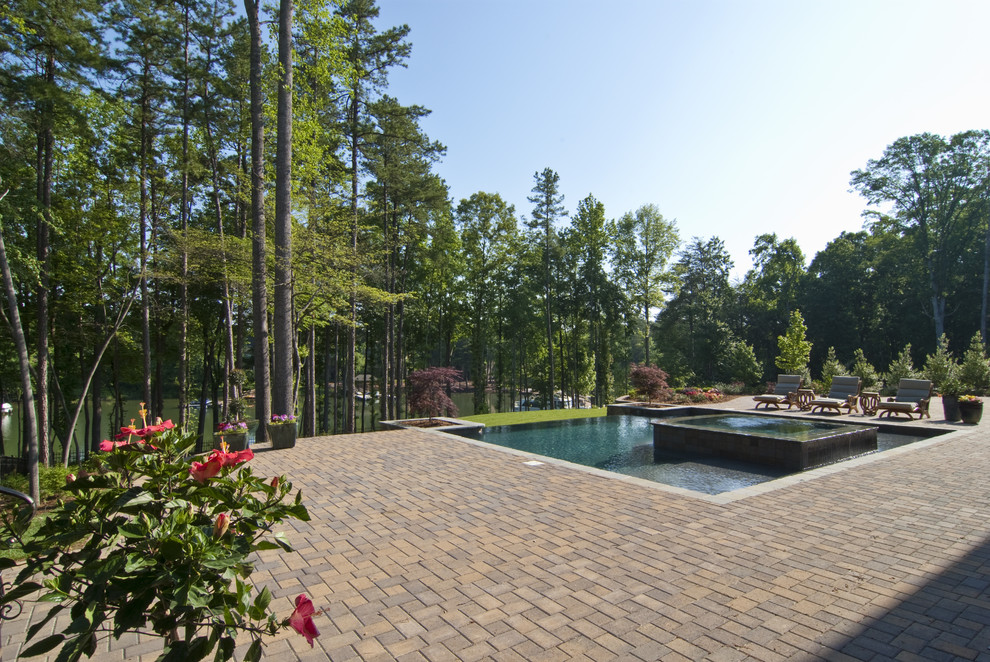 Inspiration for a large classic back rectangular hot tub in Charlotte with brick paving.