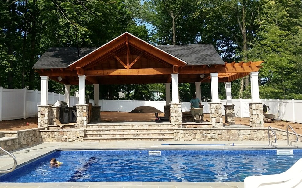 Ejemplo de casa de la piscina y piscina natural rural extra grande rectangular en patio trasero con adoquines de piedra natural