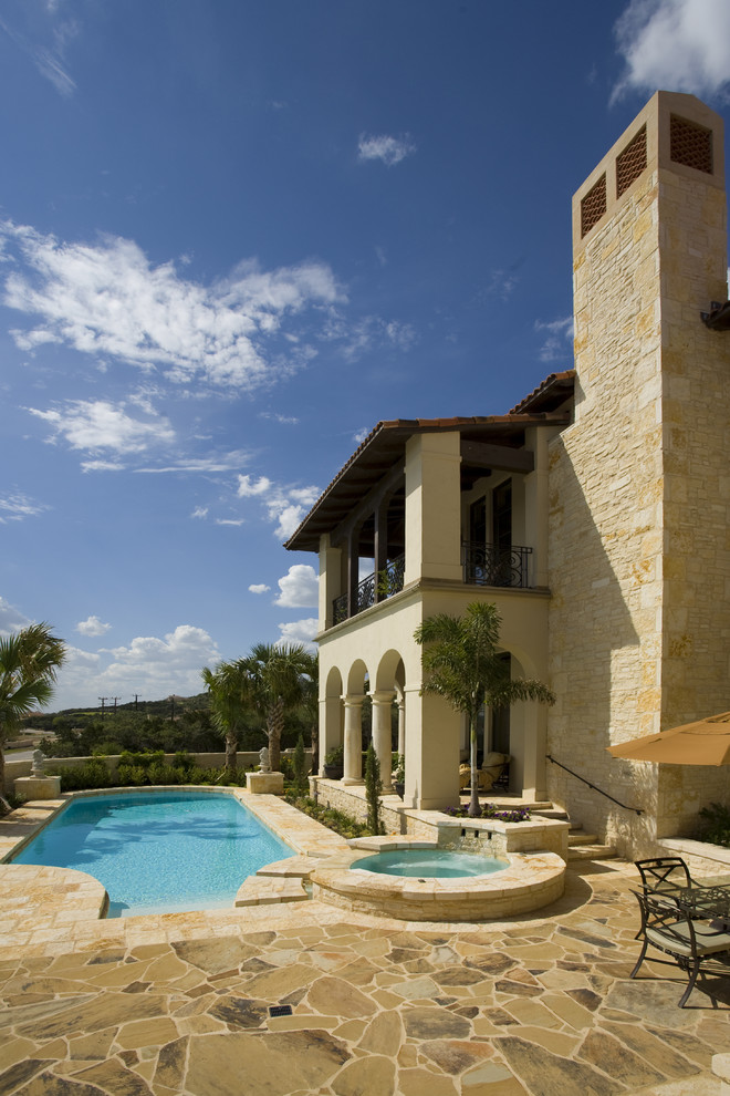 Inspiration for a mediterranean custom shaped swimming pool in Austin with natural stone paving.