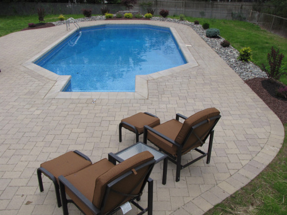 Esempio di una piscina naturale rotonda di medie dimensioni e dietro casa con lastre di cemento