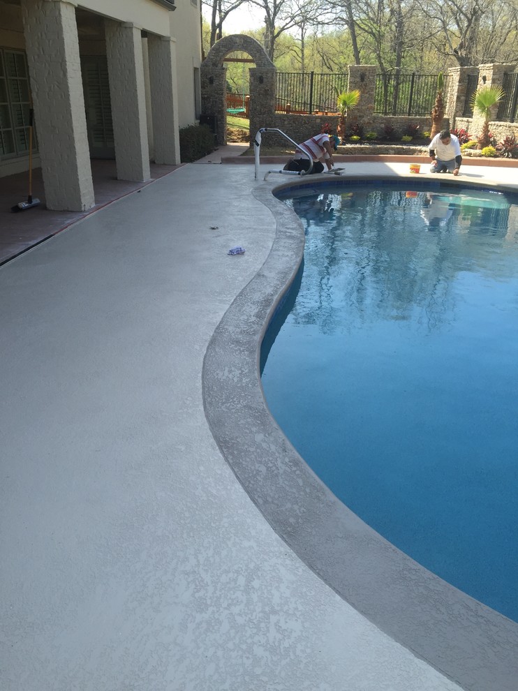 Ejemplo de piscina alargada minimalista grande tipo riñón en patio trasero con entablado