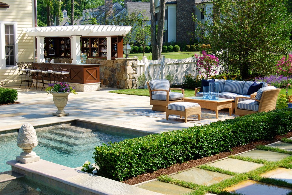 Esempio di una piscina monocorsia chic rettangolare di medie dimensioni e dietro casa con una vasca idromassaggio e pavimentazioni in pietra naturale