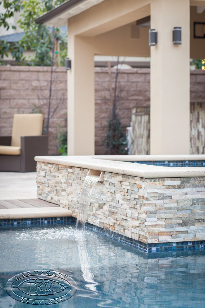 На фото: бассейн-инфинити среднего размера, произвольной формы на заднем дворе в стиле модернизм с фонтаном и покрытием из каменной брусчатки с