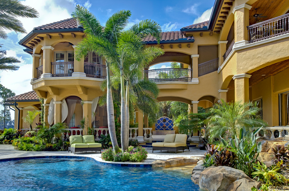 Immagine di un'ampia piscina tropicale personalizzata dietro casa con pavimentazioni in cemento