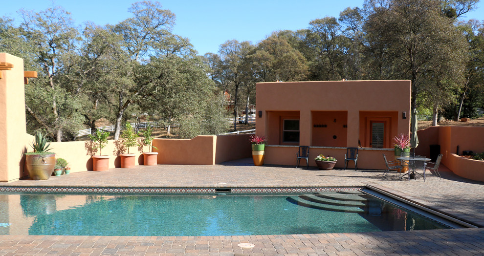 Immagine di una piscina a sfioro infinito american style rettangolare di medie dimensioni e dietro casa con una dépendance a bordo piscina e pavimentazioni in mattoni