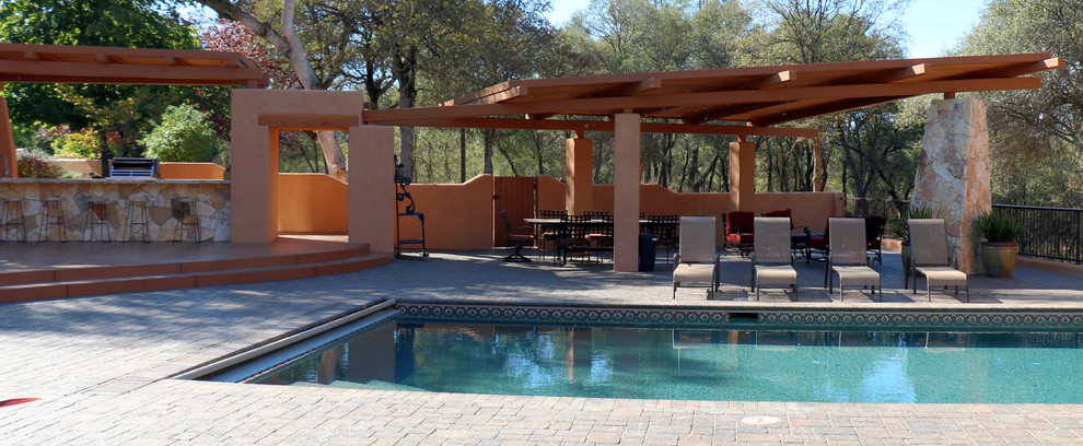 Modelo de casa de la piscina y piscina infinita de estilo americano de tamaño medio rectangular en patio trasero con adoquines de ladrillo
