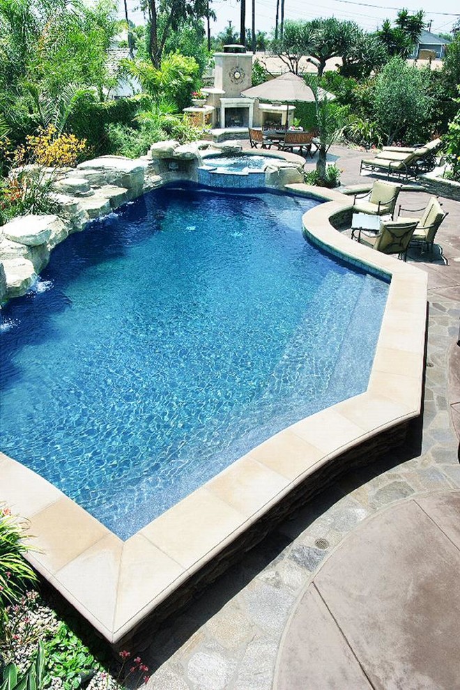 Réalisation d'une grande piscine naturelle et arrière design sur mesure avec un point d'eau et une dalle de béton.