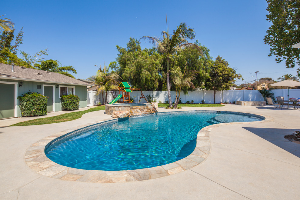 Immagine di una piscina costiera a "C" di medie dimensioni e dietro casa con una vasca idromassaggio e cemento stampato