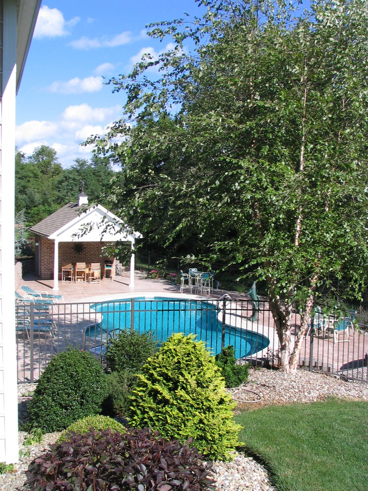 Foto di una grande piscina naturale chic a "C" dietro casa con una dépendance a bordo piscina e lastre di cemento