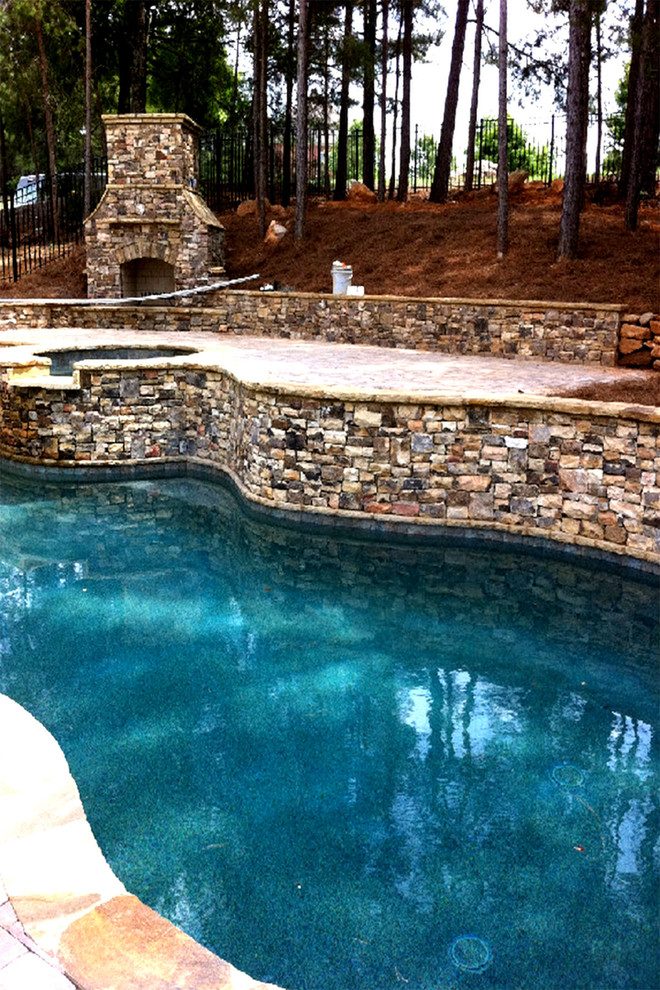 На фото: большой спортивный бассейн на заднем дворе в стиле рустика с джакузи и покрытием из каменной брусчатки с