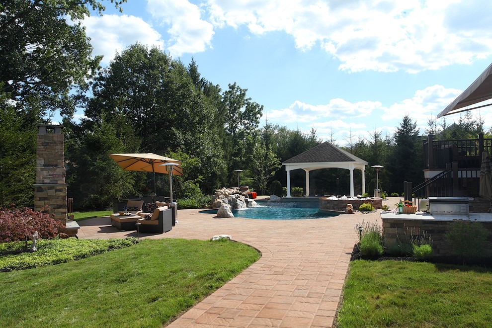 Immagine di una grande piscina tradizionale personalizzata dietro casa con una vasca idromassaggio e pavimentazioni in cemento