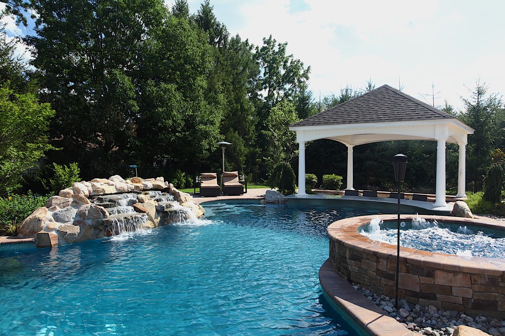 Idee per una grande piscina tropicale personalizzata dietro casa con una vasca idromassaggio e pavimentazioni in cemento