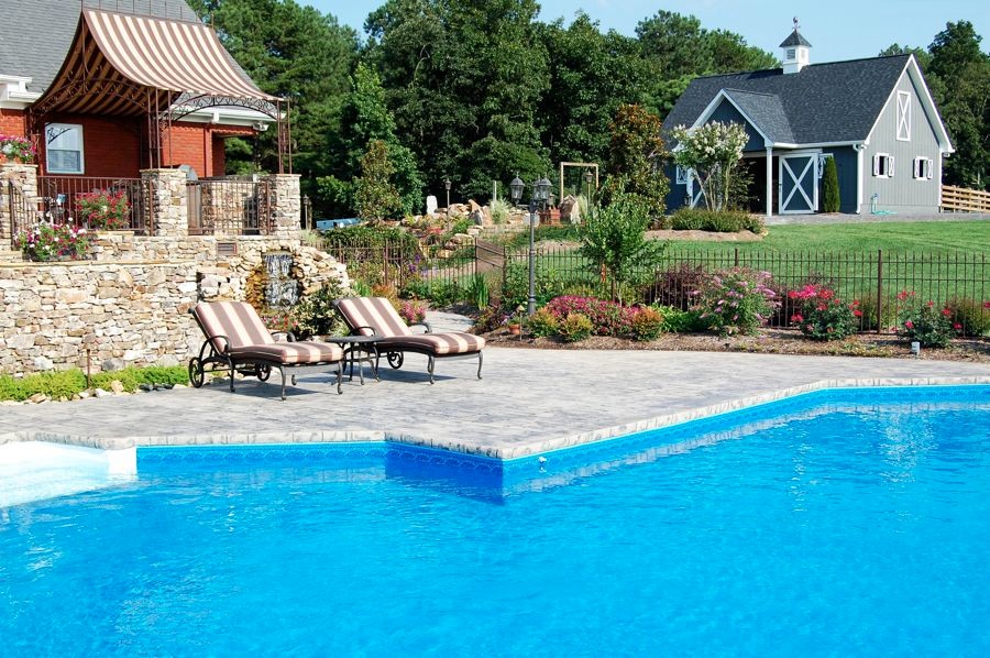 Modelo de piscina natural contemporánea de tamaño medio a medida en patio trasero con losas de hormigón