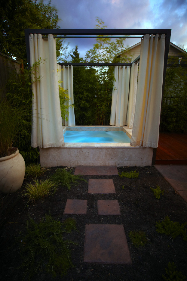 Medium sized modern back rectangular hot tub in Other with stamped concrete.