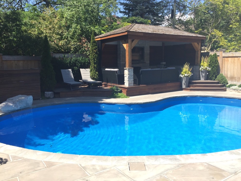 Foto de piscina con fuente alargada clásica de tamaño medio tipo riñón en patio trasero con adoquines de piedra natural