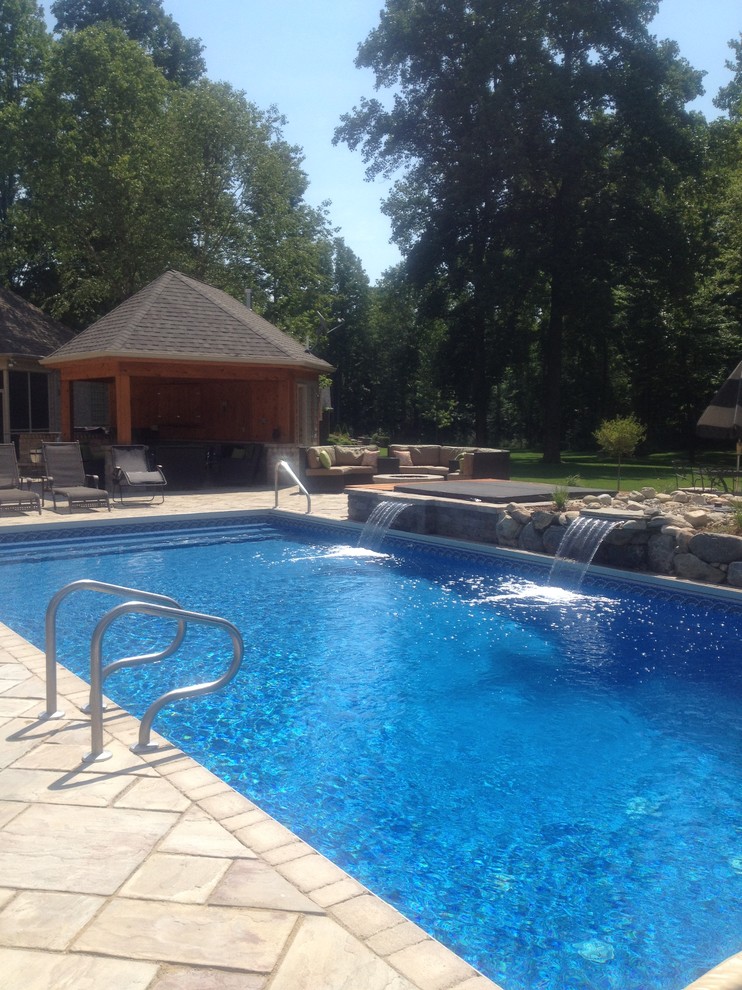 Immagine di una grande piscina coperta classica rettangolare con fontane e pavimentazioni in mattoni