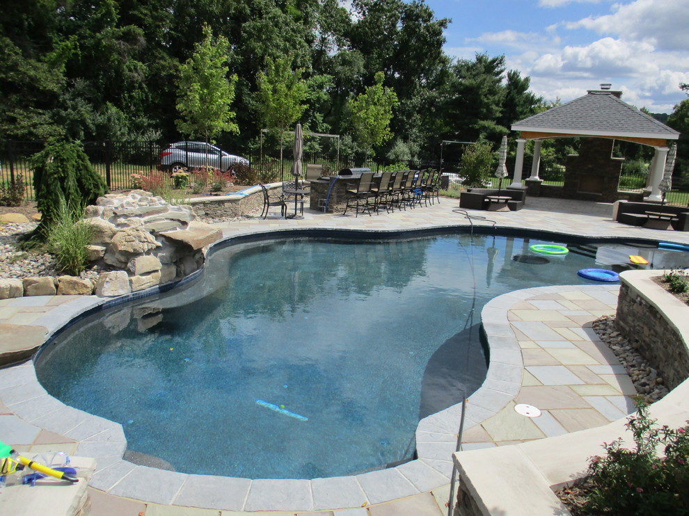 Foto de piscina con fuente natural tradicional grande a medida en patio trasero con adoquines de ladrillo