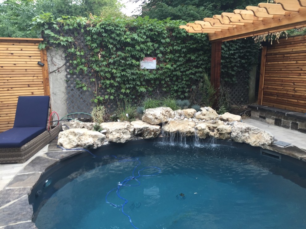 Foto di una grande piscina a sfioro infinito classica rotonda dietro casa con una dépendance a bordo piscina e pavimentazioni in pietra naturale
