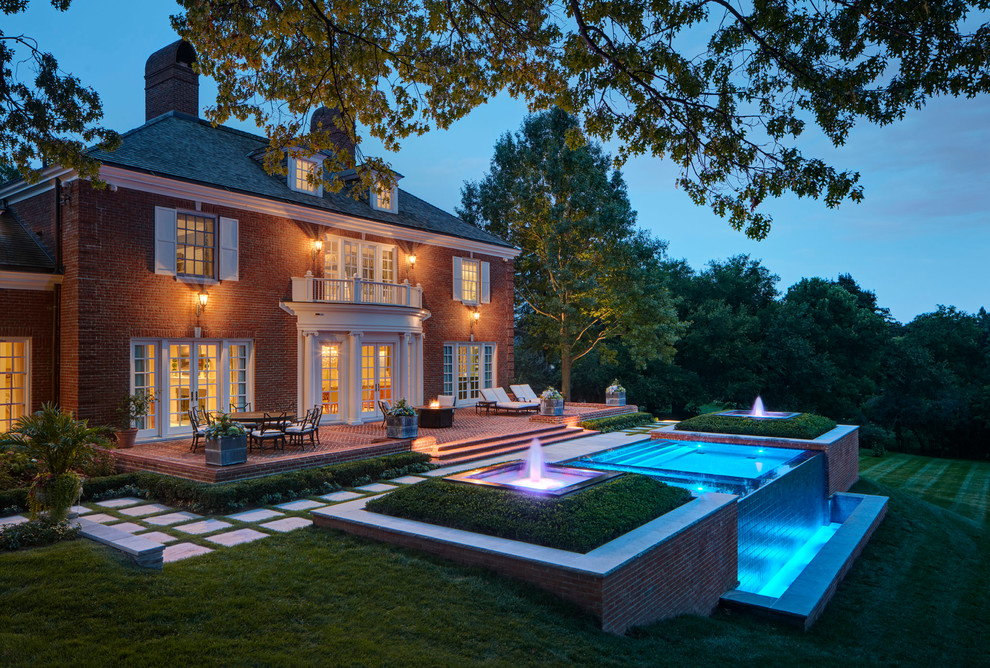 Traditional back infinity swimming pool in Detroit with a water feature.