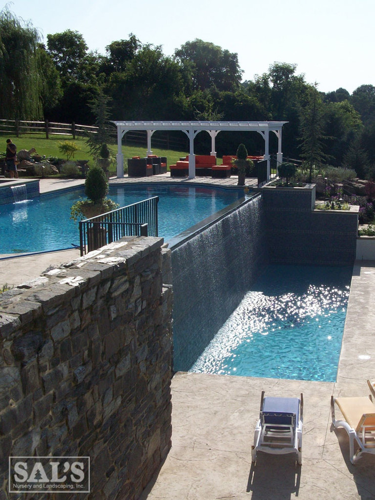 Modelo de piscina moderna extra grande a medida en patio trasero con adoquines de piedra natural