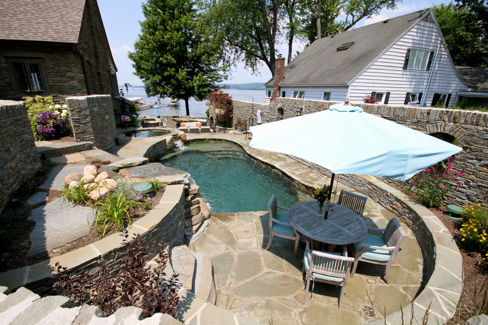 Imagen de piscina con fuente natural ecléctica de tamaño medio a medida en patio lateral con adoquines de piedra natural