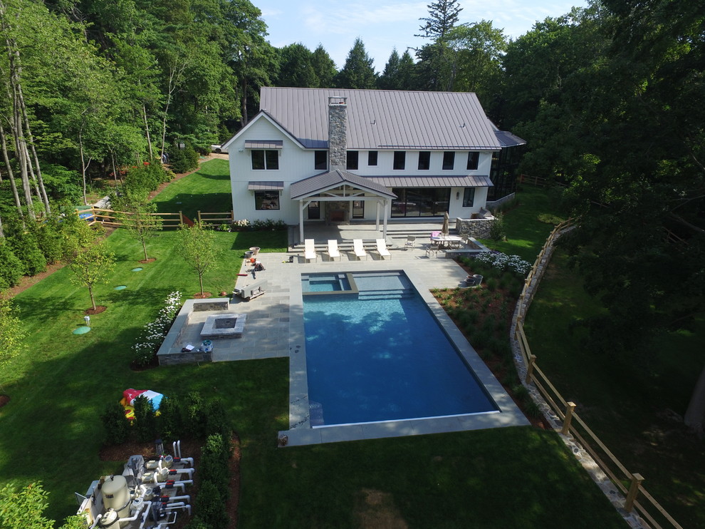 Foto de piscinas y jacuzzis actuales grandes rectangulares en patio trasero con adoquines de piedra natural