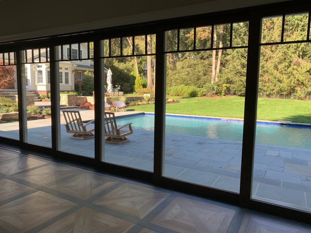 Modelo de casa de la piscina y piscina natural clásica grande rectangular en patio trasero con adoquines de piedra natural