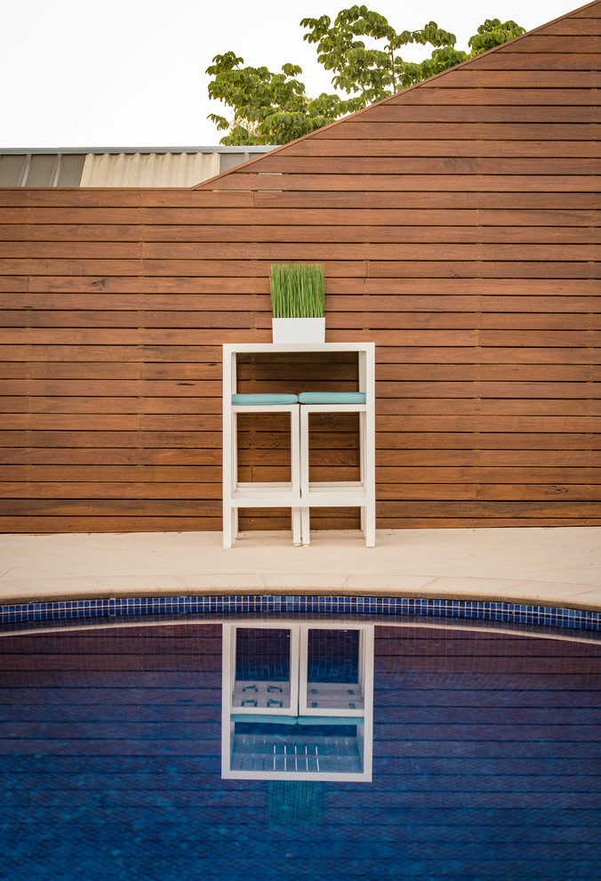 Diseño de piscina contemporánea grande en patio trasero con adoquines de piedra natural