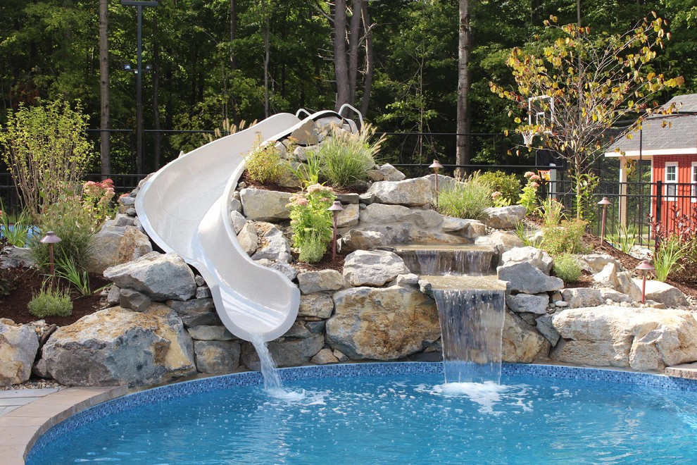 Photo of an expansive classic back kidney-shaped lengths swimming pool in Boston with a water slide and tiled flooring.