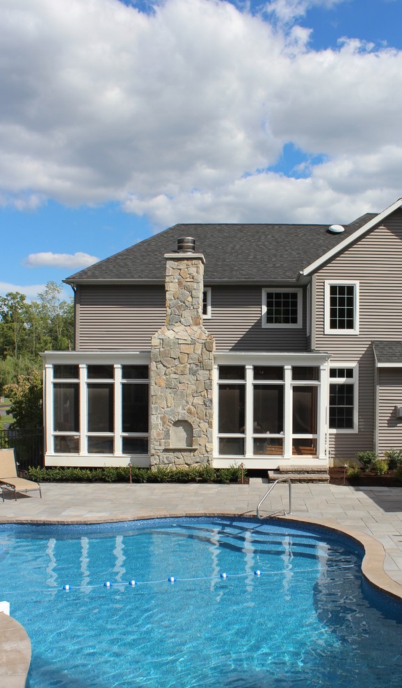 Esempio di una grande piscina monocorsia american style personalizzata dietro casa con una dépendance a bordo piscina e pavimentazioni in pietra naturale