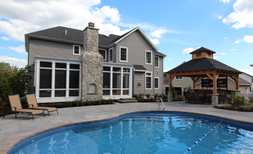 Diseño de casa de la piscina y piscina alargada de estilo americano grande a medida en patio trasero con adoquines de piedra natural