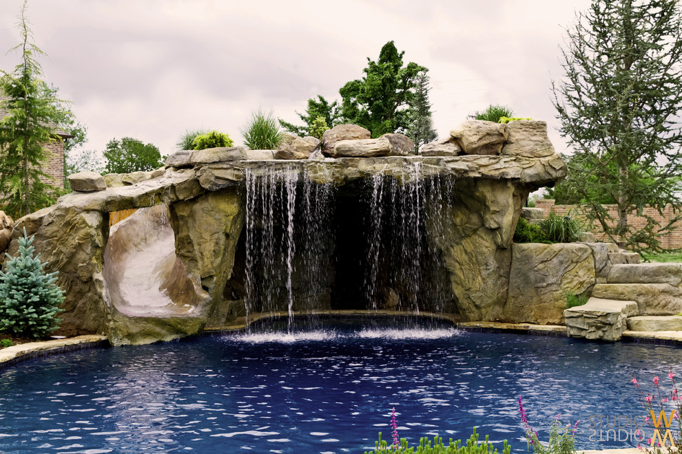 Medium sized classic back custom shaped lengths swimming pool in Oklahoma City with a water feature and natural stone paving.