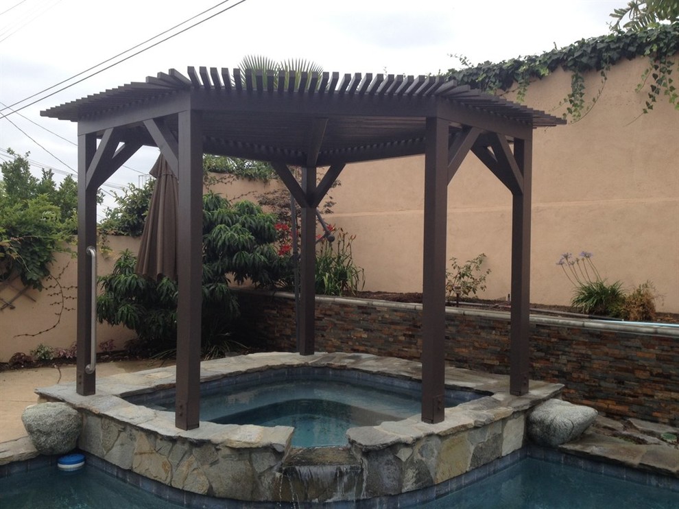 Diseño de piscinas y jacuzzis elevados de estilo americano grandes a medida en patio trasero con adoquines de piedra natural