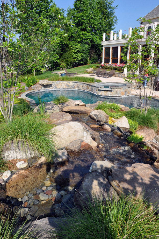 Ispirazione per un'ampia piscina naturale eclettica personalizzata dietro casa con una dépendance a bordo piscina e pavimentazioni in pietra naturale