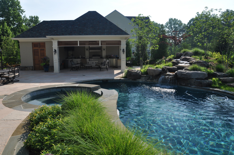 Photo of an expansive eclectic back custom shaped natural swimming pool in Baltimore with a pool house and natural stone paving.