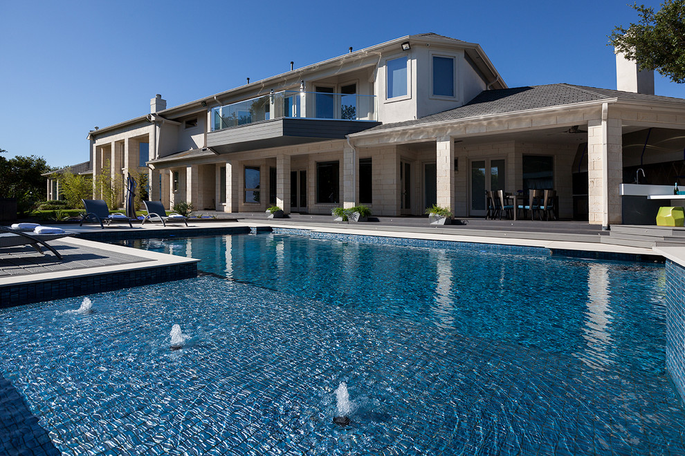 Esempio di una grande piscina monocorsia design rettangolare dietro casa con una vasca idromassaggio e pavimentazioni in cemento