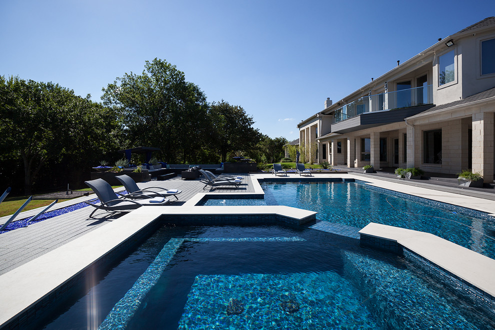 Modelo de piscinas y jacuzzis alargados actuales grandes rectangulares en patio trasero con adoquines de hormigón