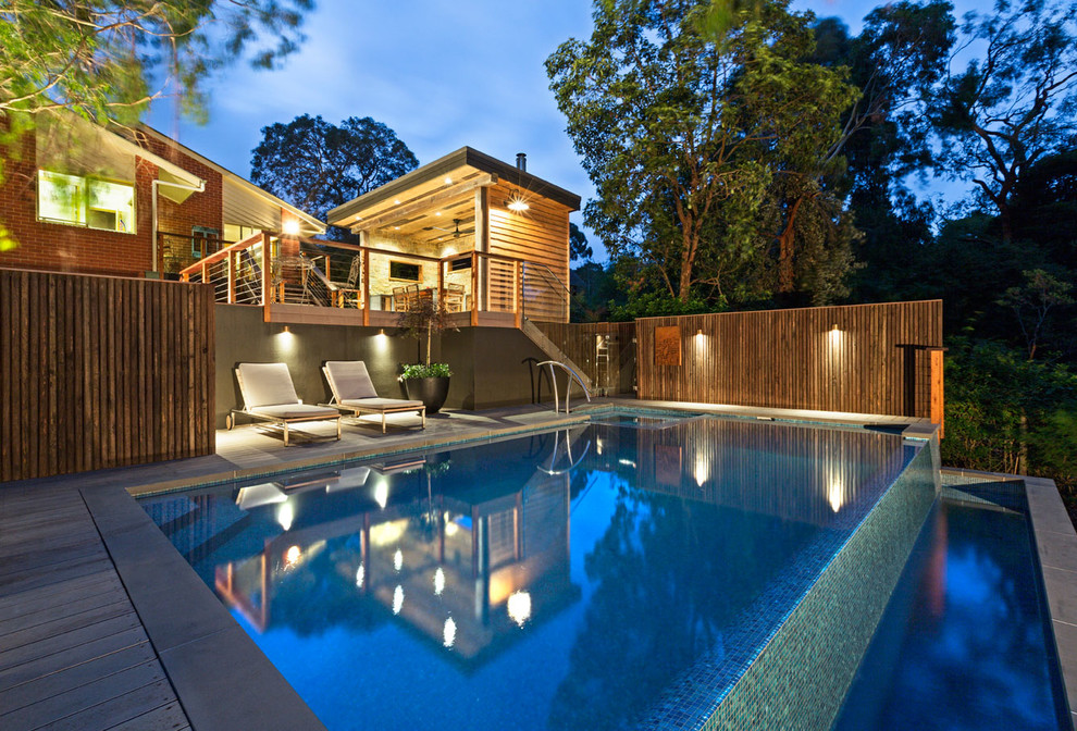 Ejemplo de casa de la piscina y piscina infinita contemporánea de tamaño medio rectangular en patio trasero con suelo de baldosas