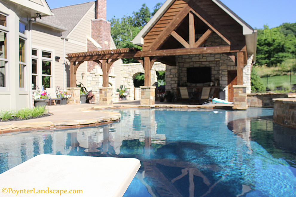 Large classic back custom shaped natural swimming pool in St Louis with a pool house and stamped concrete.