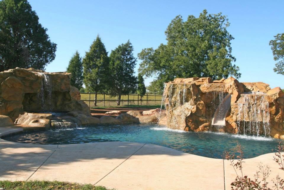 Idee per una grande piscina naturale tradizionale personalizzata dietro casa con un acquascivolo e pavimentazioni in cemento